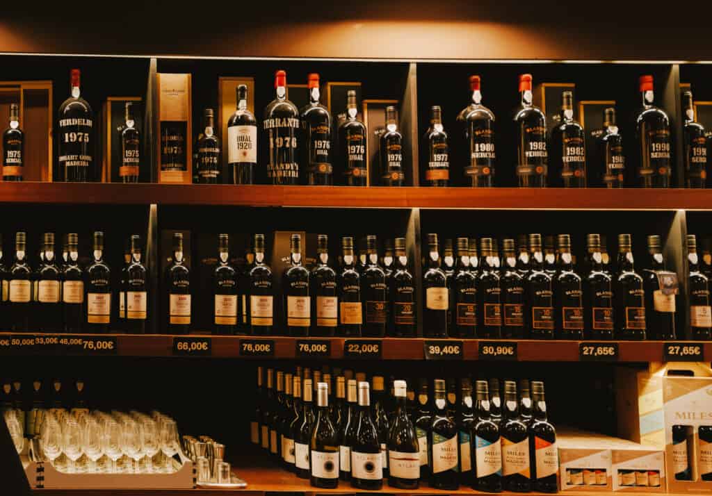 a wall inside a Madeira winery stacked to the with a variety of famous wines from around the country