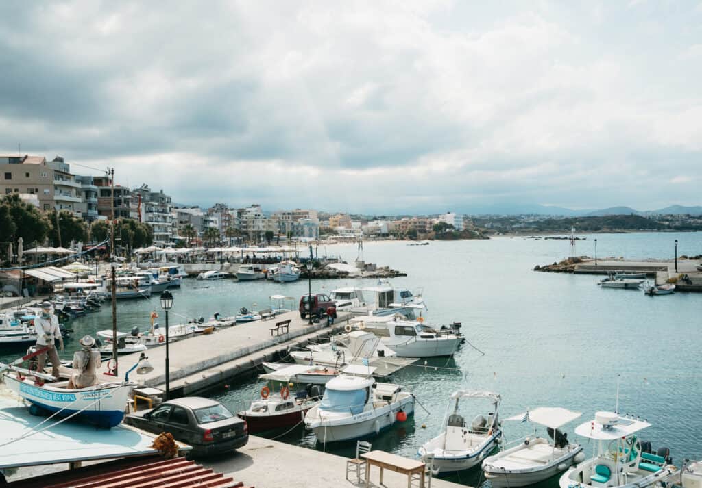 Looking down at the port at Nea Chora Beach in Chania, Crete. There are several boats docked along the port