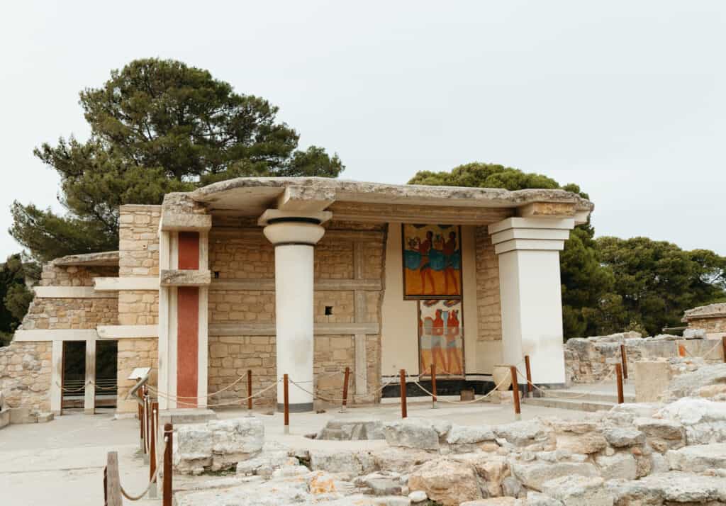 The reconstructed ruins of the Knossos Palace in Crete, Greece, featuring a section with Minoan frescoes and columns.