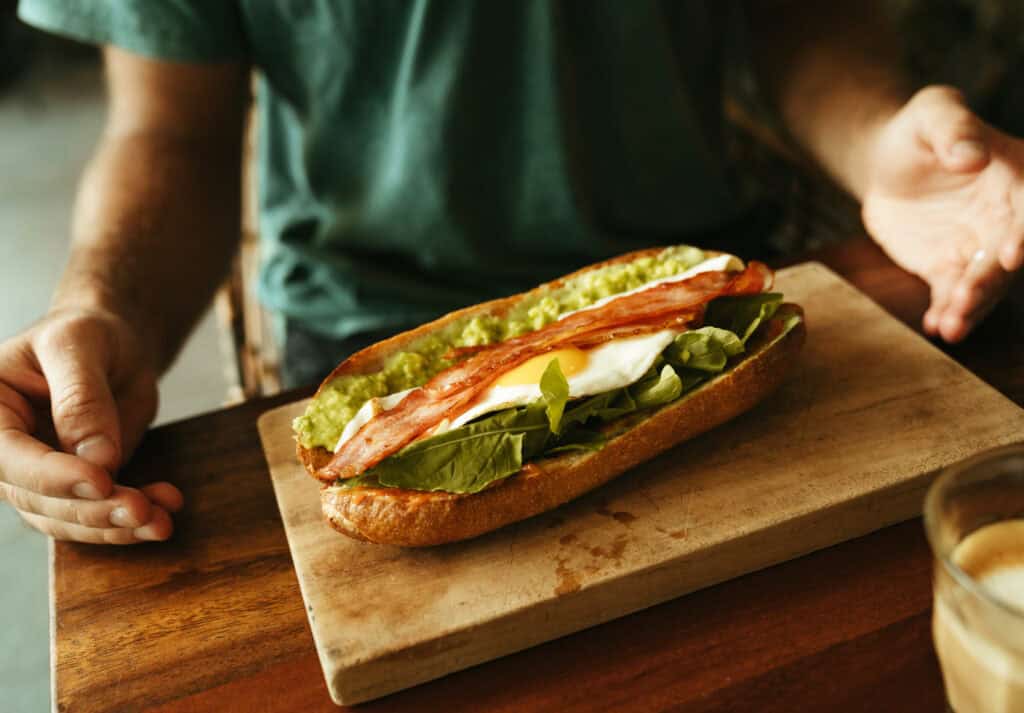 A close-up view of a hearty breakfast in Canggu, featuring a breajfast sandwich with avocado, megg and bacon. Sprout is also a fantastic cafe for brunch in Canggu