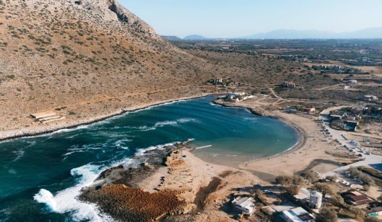 drone view of Stavros Beach, Crete. The water is an incredible blue and you can see the mountains towering over the ocean