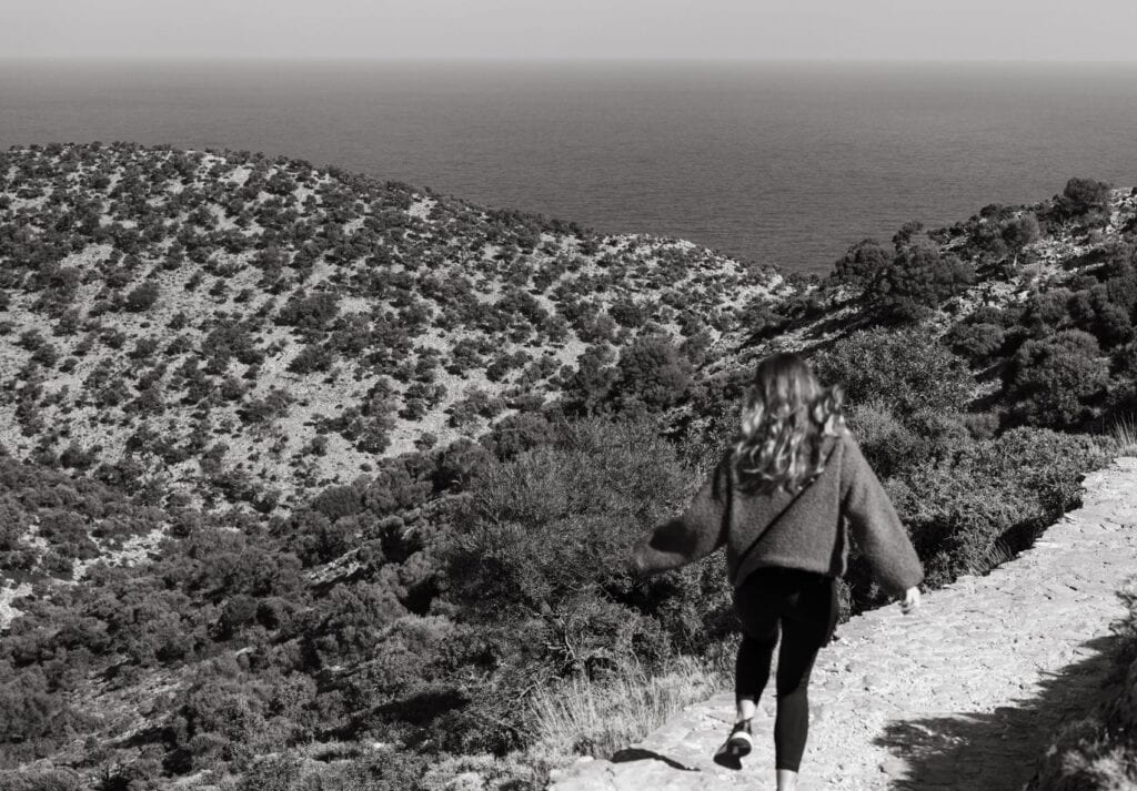 Black and white image of Sarah hiking along the coastal cliffs of Crete, Greece.