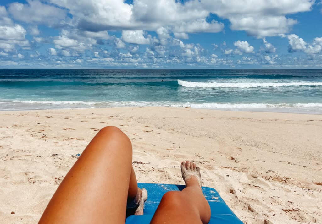 Sarah lounging out in the sun at the beach in Canggu. You can see the stunning blue ocean waves crashing onto shore