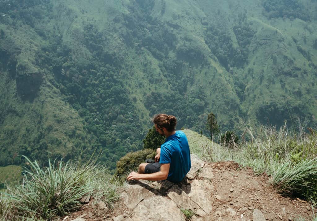 Caleb sitting on the edge of Ella Rock in Sri Lanka